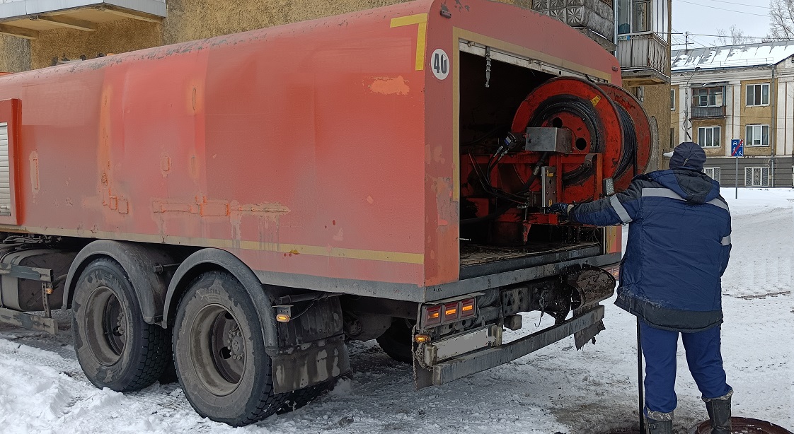 Каналопромывочная машина и работник прочищают засор в канализационной системе в Богучанах