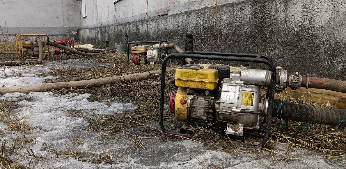 Откачка мотопомпами талой воды из подвала дома в Лесосибирске